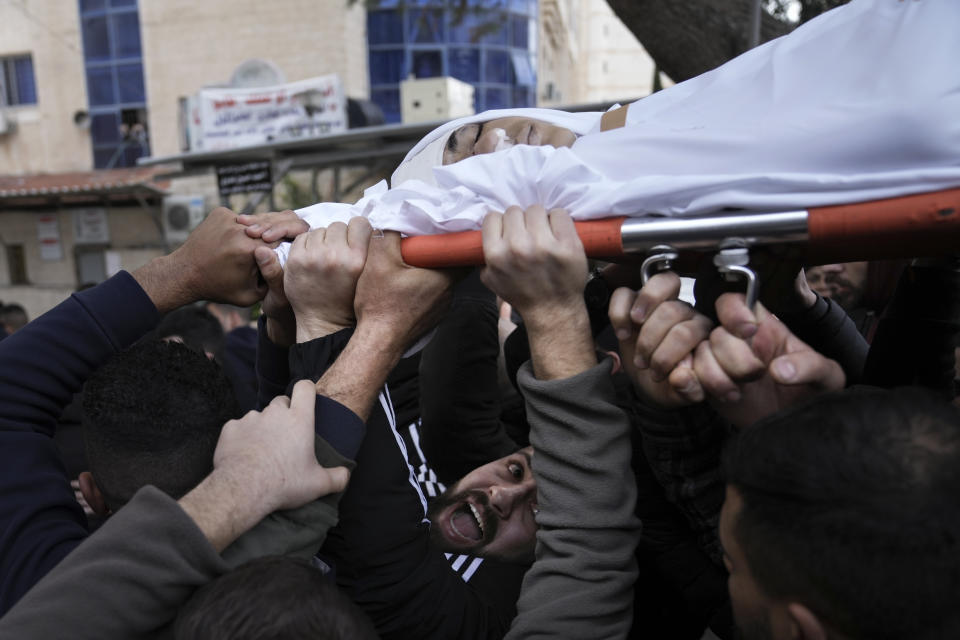 Mourners carry the body of 14-year-old Palestinian Omar Khumour during his funeral in the West Bank city of Bethlehem, Monday, Jan. 16, 2023. The Palestinian Health Ministry said Khumour died after being struck in the head by a bullet during an Israeli military raid into Dheisha refugee camp near the city of Bethlehem. The Israeli army said that forces entered the Dheisha camp and were bombarded by Molotov cocktails and rocks. It said soldiers responded to the onslaught with live fire. (AP Photo/Mahmoud Illean)