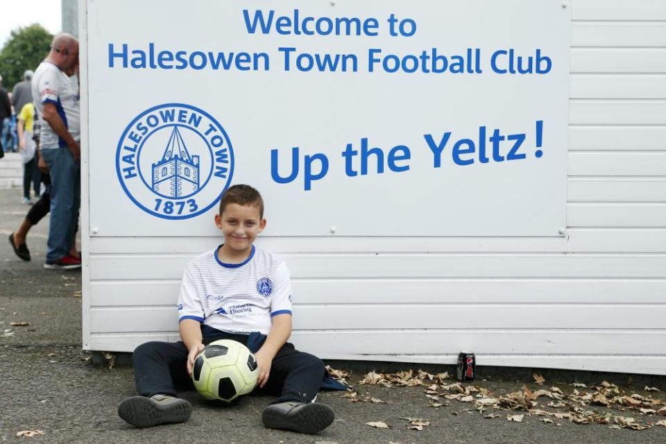 Ένας νεαρός θαυμαστής του Halesowen μπροστά από μια πινακίδα που λέει Up the Yeltz