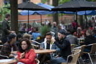 Members of the public are seen at a bar on Canal Street in Manchester's gay village, England, Saturday July 4, 2020. England is embarking on perhaps its biggest lockdown easing yet as pubs and restaurants have the right to reopen for the first time in more than three months. In addition to the reopening of much of the hospitality sector, couples can tie the knot once again, while many of those who have had enough of their lockdown hair can finally get a trim. (AP Photo/Jon Super)