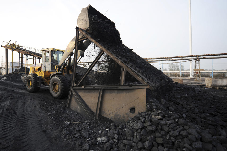 A worker use heavy machinery to move coal at the yard of a coal mine in Huaibei in central China's Anhui province on Nov. 3, 2016. China, the world's biggest coal user, said Tuesday, April 27, 2021 that the fossil fuel will play a less dominant role in its energy mix and that, despite plans to build new coal-fired power plants, the country won't use it on a wide scale. (Chinatopix via AP)