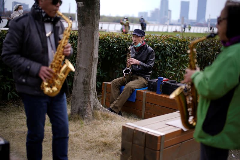 A man wears his face mask on his chin while he plays the saxophone at a park as the country is hit by an outbreak of the novel coronavirus COVID-19, in Shanghai