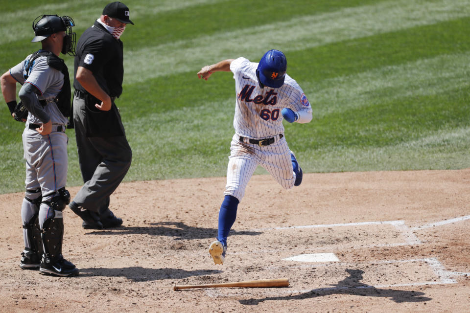 Home plate umpire Mark Carlson (6) watches as New York Mets Andres Gimenez (60) leaps over the plate after scoring on Corey Dickerson's fielding error during the fourth inning of a baseball game at Citi Field, Sunday, Aug. 9, 2020, in New York. Miami Marlins catcher Ryan Lavarnway is at left. (AP Photo/Kathy Willens)