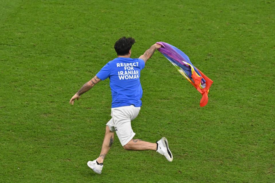 A man invades the pitch holding a LGBT flag as he wears a t-shirt reading “Respect for Iranian woman” (GLYN KIRK/AFP via Getty Images)