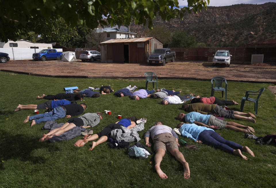 FILE - Participants lay face down on the grass during an integration circle at an ayahuasca retreat in Hildale, Utah, on Saturday, Oct. 15, 2022. Following each of the three ayahuasca ceremonies, Hummingbird Church asks their participants to partake in integration, or a group reflection and discussion, to help interpret messages they received from the ayahuasca. (AP Photo/Jessie Wardarski, File)
