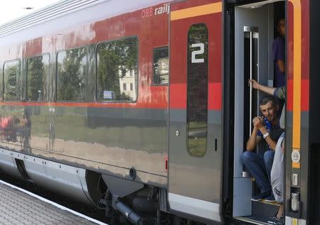 Travellers sit on the stairs of a wagon as a train heading for Austria, with migrants on board, is stopped for checks at a border station in Hegyeshalom, Hungary, August 31, 2015. REUTERS/Heinz-Peter Bader