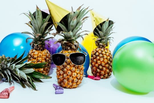 Pineapples with sunglasses and balloons having a party