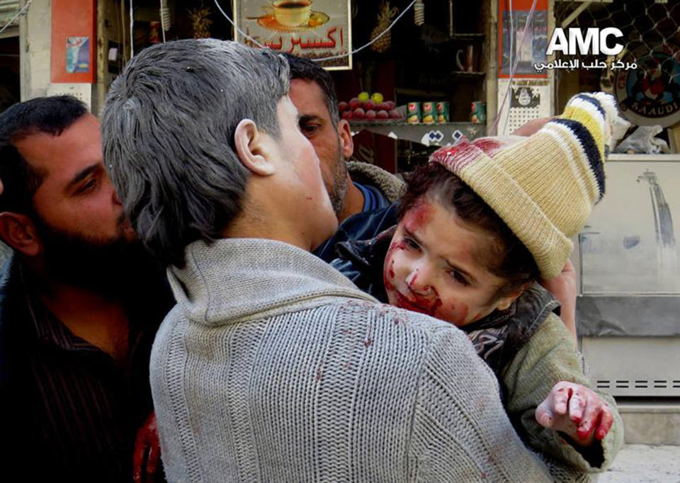 This photo provided by the anti-government activist group Aleppo Media Center (AMC), which has been authenticated based on its contents and other AP reporting, shows a Syrian man carrying a wounded child following a Syrian government airstrike in Aleppo, Syria, Monday, Feb. 3, 2014. Syrian government helicopters and warplanes unleashed a wave of airstrikes on more than a dozen opposition-held neighborhoods in the northern city of Aleppo on Sunday, firing missiles and dropping crude barrel bombs in a ferocious attack that killed at least 36 people, including children, activists said. (AP Photo/Aleppo Media Center, AMC)