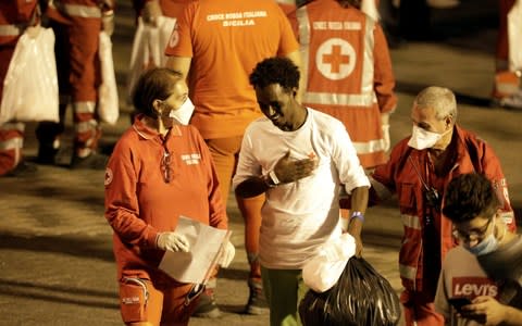  A migrant is helped by Red Cross members after disembarking from Italian coast guard vessel "Diciotti"  - Credit:  ANTONIO PARRINELLO/ REUTERS