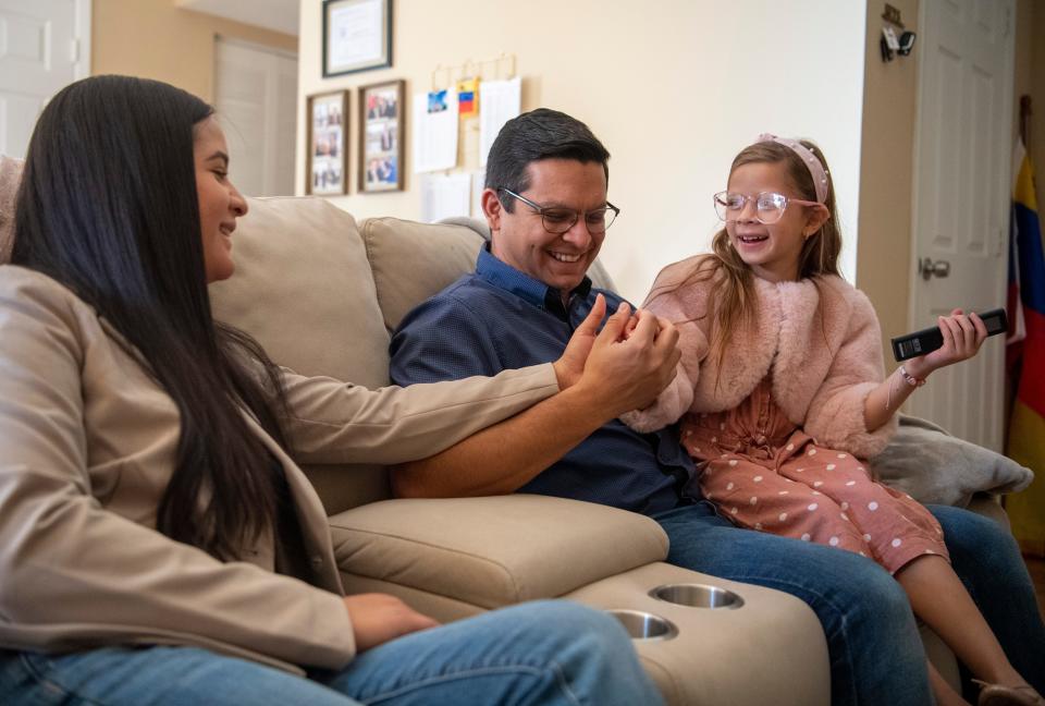 Jesus Alejandro Segovia and his wife Verleijh Toro share a laugh with their eight-year-old daughter Paula Melo as they watch tv Friday morning, Oct. 28, 2022.