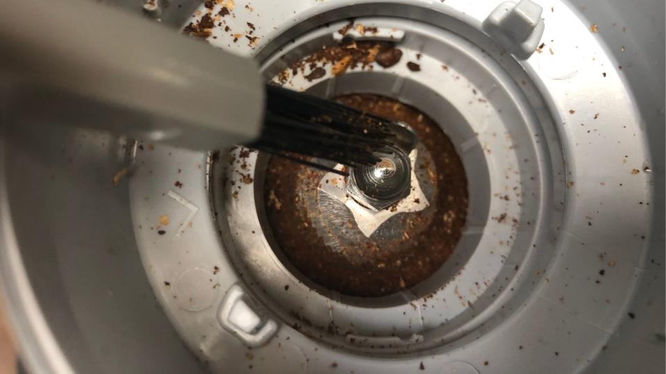 Using a small brush to clean out a coffee maker