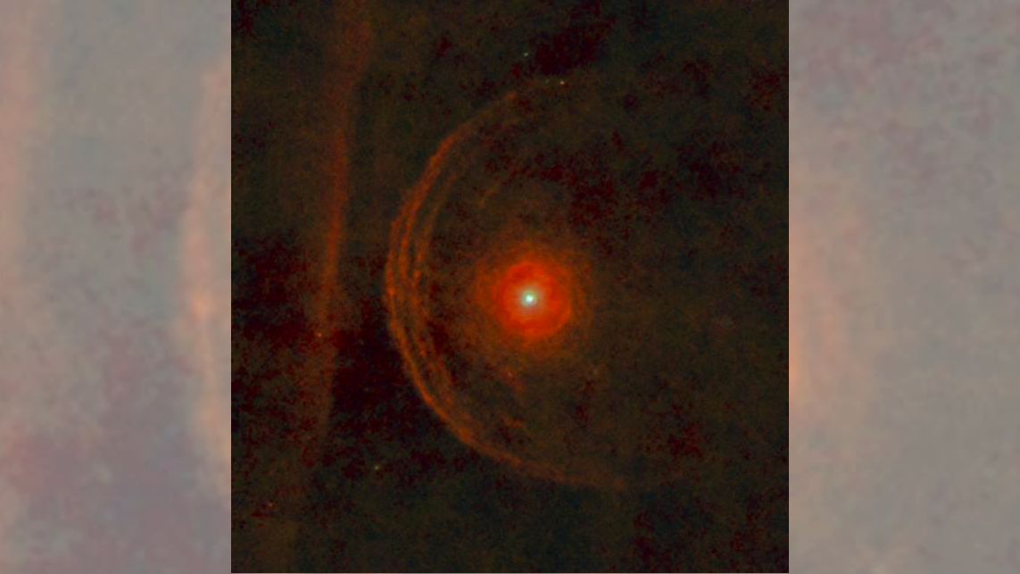  We see the red star Betelgeuse surrounded by rings of hazy red material. 