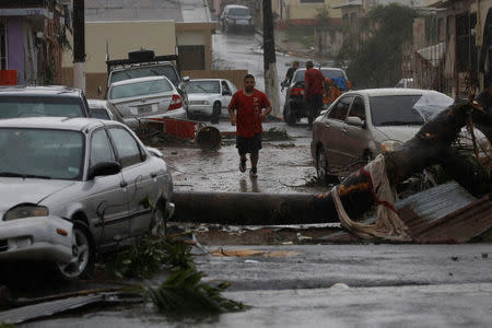 A man runs on the street next to debris and damaged cars after the area was hit by Hurricane Maria in Guayama, Puerto Rico September 20, 2017. REUTERS/Carlos Garcia Rawlins