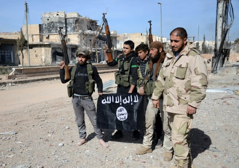 Rebel fighters, part of the Turkey-backed Euphrates Shield alliance, pose with an Islamic State group flag as they advance on February 20, 2017, towards the city of Al-Bab, some 30 kilometres from the Syrian city of Aleppo