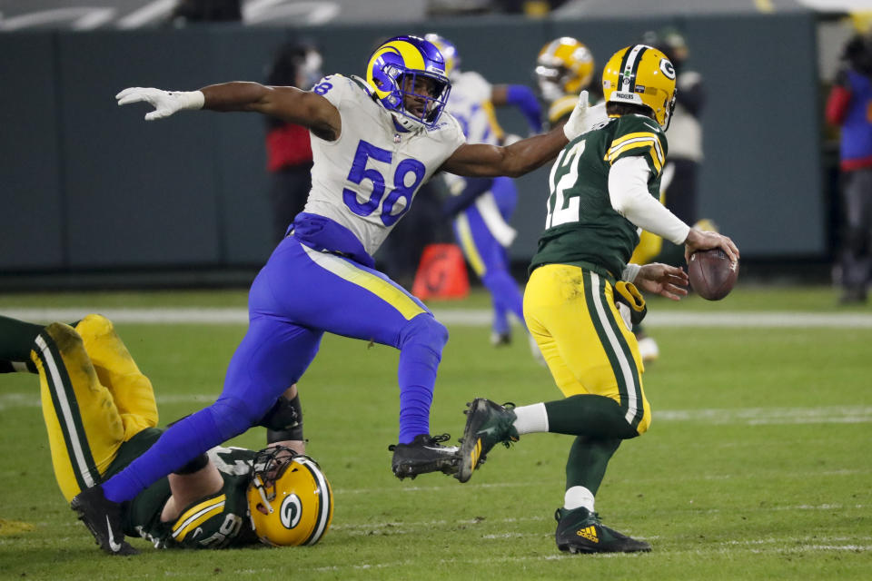 Green Bay Packers quarterback Aaron Rodgers is chased by Los Angeles Rams' Justin Hollins during the second half of an NFL divisional playoff football game Saturday, Jan. 16, 2021, in Green Bay, Wis. (AP Photo/Mike Roemer)