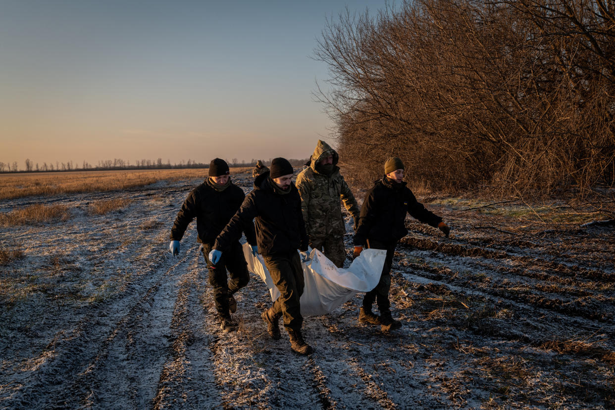 Members of a humanitarian group carry the body of a Russian serviceman near Koroviy Yar, in the Donetsk region of Ukraine, Jan. 7, 2023. (Nicole Tung/The New York Times)