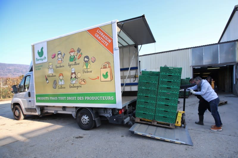 A staff of Farmy.ch, an online shop for home delivery of regional and organic products, loads fruits and vegetables from the "Le Domaine des Biolettes" farm