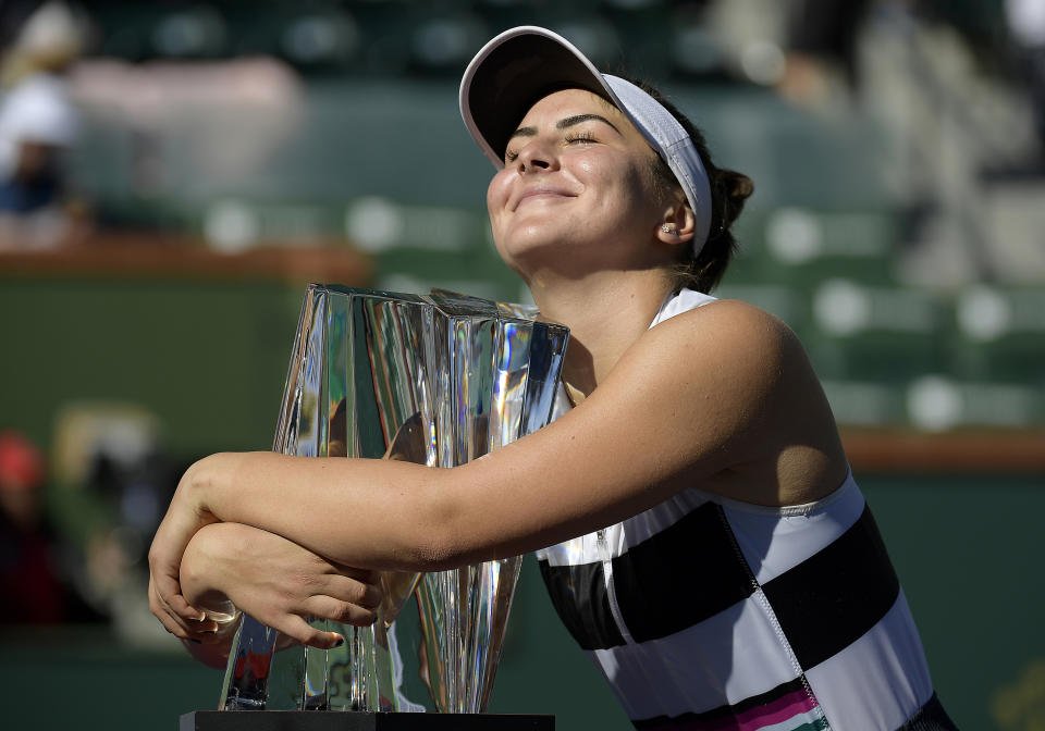 FILE - In this Sunday, March 17, 2019, file photo, Bianca Andreescu, of Canada, smiles as she hugs her trophy after defeating Angelique Kerber, of Germany, in the women's final at the BNP Paribas Open tennis tournament, in Indian Wells, Calif. Roger Federer has won one trophy so far in 2019, which puts him in a tie for the ATP lead, with 18 other players. That same sort of unprecedented parity is going on in the WTA, with 13 different champions from 13 tournaments. (AP Photo/Mark J. Terrill, File)