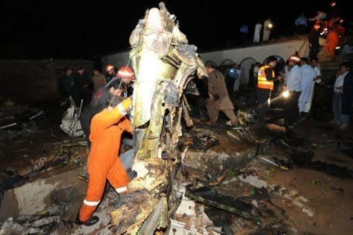 Pakistani rescue workers and local residents search the site of a plane crash in Rawalpindi. A passenger airliner crashed near Islamabad on Friday while trying to land during a thunderstorm, officials said, with all 127 people on board believed dead