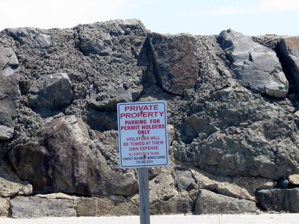 A sign is displayed near the sea wall in Sea Bright N.J., on May 15, 2021, prohibiting public parking. Some shore towns in New Jersey and other states have used parking restrictions as a way to keep outsiders off their beaches. Sea Bright does offer a public parking lot near one beach. (AP Photo/Wayne Parry)