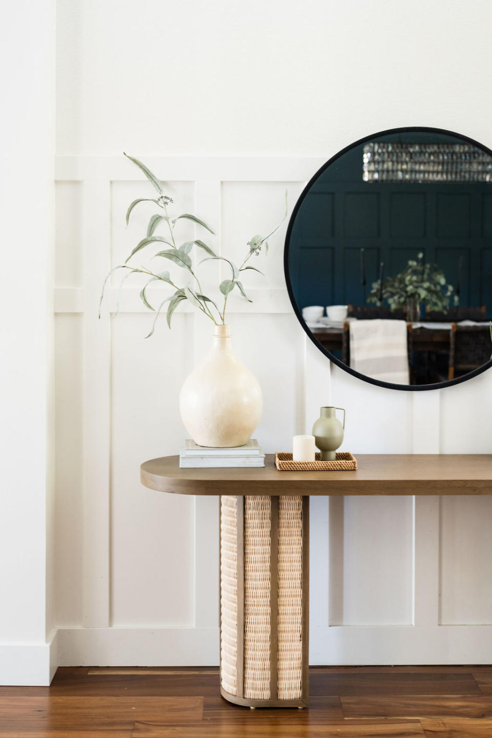 A credenza with a circular mirror above it