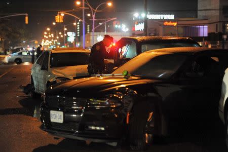 A New York City police officer inspects cars at a crash site in the Brooklyn borough in New York, November 26, 2015. REUTERS/Stephanie Keith