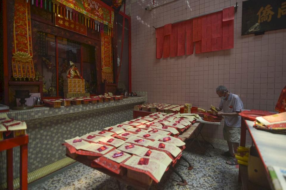 To help move visitors along, Sin Size Si Ya Taoist temple staff assist visitors with prayer requests. This is part of the Taoist temple's own initiative to minimise visitors inside the temple. — Picture by Miera Zulyana