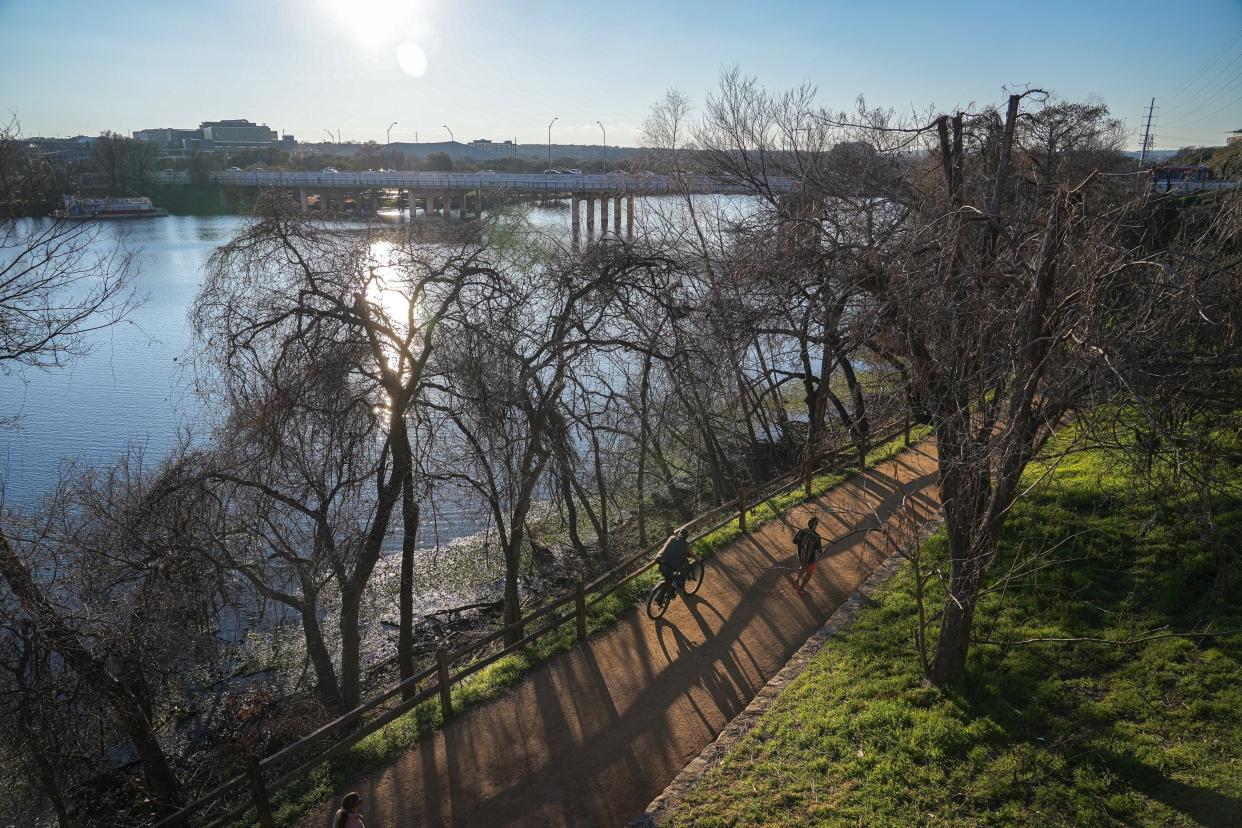 Pedestrians use a trail near where a body was found Monday in Lady Bird Lake near the South First Street bridge.