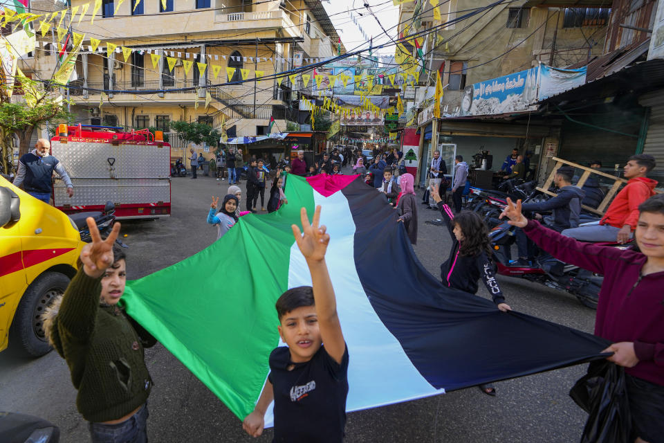 Palestinian children hold a giant Palestinian flag, during the observance of a global day of boycotts and strikes called for by pro-Palestinian activists to demand a cease-fire in Gaza, at Bourj al-Barajneh Palestinian refugee camp in Beirut, Lebanon, Monday, Dec. 11, 2023. Public agencies, schools and banks were shuttered in Lebanon Monday in observance of a global day of boycotts and strikes called for by pro-Palestinian activists to demand a ceasefire in Gaza. (AP Photo/Bilal Hussein)