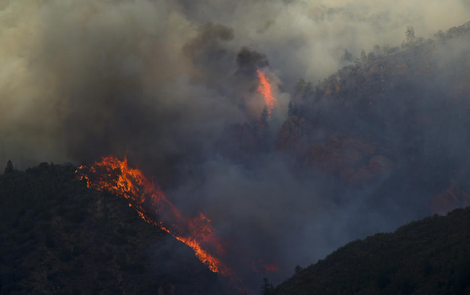 In this Wednesday, Sept. 12, 2018, photo hot spots flare up near a rock formation a wildfire burns in northern Juab County, Utah. A fast-moving Utah wildfire fanned by high-winds has more than doubled in size as it burns through dry terrain and forces evacuations of hundreds of homes, the U.S. Forest Service said Friday. (Isaac Hale/The Daily Herald via AP)