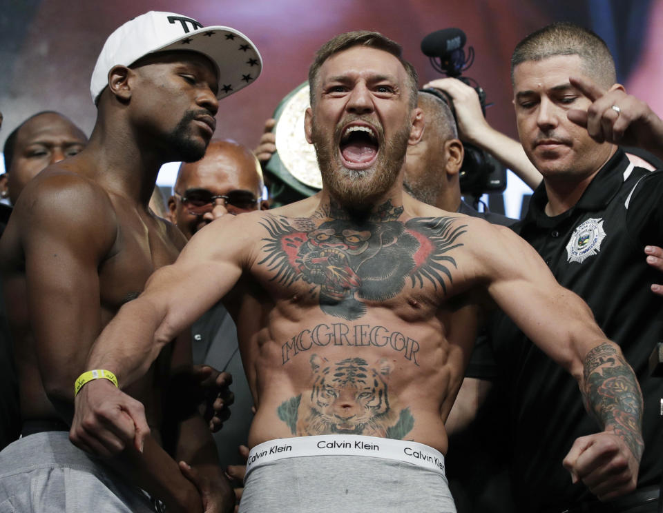 2017 AP YEAR END PHOTOS – Conor McGregor, center, stands next to Floyd Mayweather Jr., center left, during their weigh-in on Aug. 25, 2017, the day before their boxing match in Las Vegas. (AP Photo/John Locher)