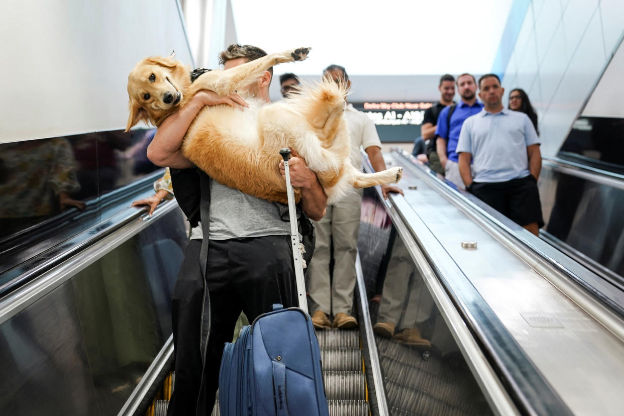 Matthew Mottola carries his dog Luca down an escalator at Hartsfield-Jackson Atlanta International Airport ahead of the Fourth of July holiday in Atlanta, Georgia, U.S., July 1, 2022.  REUTERS/Elijah Nouvelage