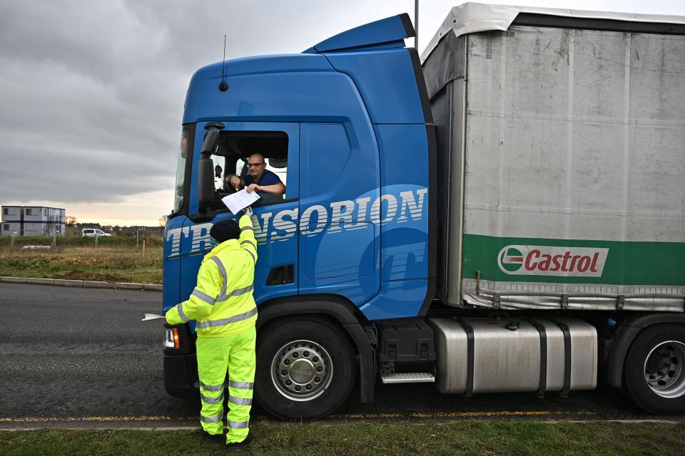 A traffic marshall checks the documents of a freight lorry driver at Waterbrook Park facility in Ashford, south east England on January 15, 2021, as hauliers get used to life under the post-Brexit trade deal. - British companies are struggling with a large amount of red tape as a result of Brexit, with senior government minister Michael Gove recently admitting that there would be "significant disruption" at the border because of increased bureaucracy that is slowing the flow of freight. (Photo by BEN STANSALL / AFP) (Photo by BEN STANSALL/AFP via Getty Images)