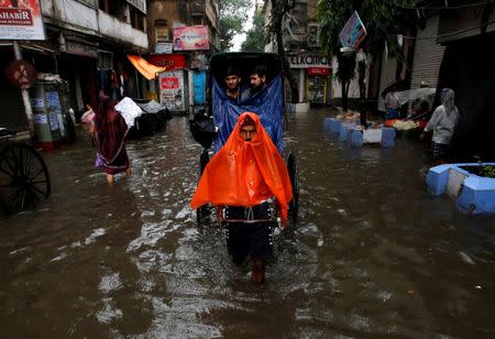 A rickshaw puller transports passengers through a water-logged street after heavy rain in Kolkata, India, June 26, 2018. REUTERS/Rupak De Chowdhuri