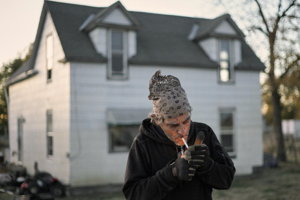 In this Tuesday, Oct. 22, 2019 photo, Marty Study lights a cigarette in front of his flood-damaged home in Bartlett, Iowa. Study has lived in a trailer since the March floods and had to be rescued from a second-floor window when his house flooded. Flooding along the Missouri River has stretched on for seven months in places and could endure through the winter, leaving some Upper Midwest farmland and possibly some homes encased in ice. (AP Photo/Nati Harnik)