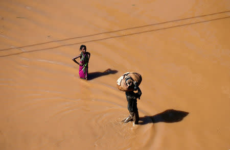 A girl stops to look as a man walks past carrying luggage on his head after Cyclone Idai in Buzi district outside Beira, Mozambique, March 22, 2019. REUTERS/Siphiwe Sibeko