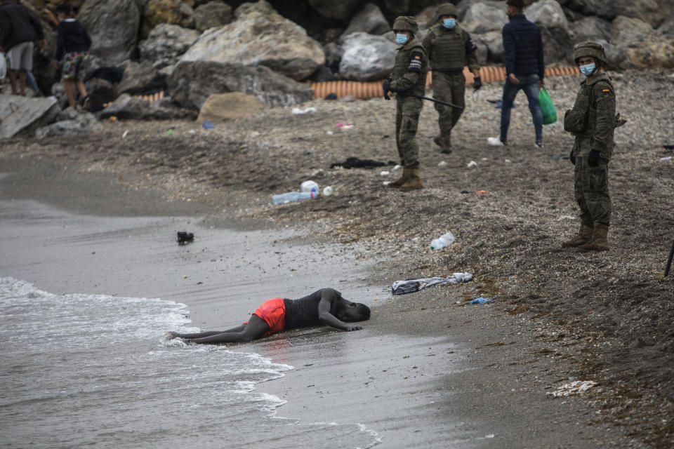 A man lies on the ground as Spanish Army cordon off the area at the border of Morocco and Spain, at the Spanish enclave of Ceuta, on Tuesday, May 18, 2021. Ceuta, a Spanish city of 85,000 in northern Africa, faces a humanitarian crisis after thousands of Moroccans took advantage of relaxed border control in their country to swim or paddle in inflatable boats into European soil. Around 6,000 people had crossed by Tuesday morning since the first arrivals began in the early hours of Monday, including 1,500 who are presumed to be teenagers. (AP Photo/Javier Fergo)