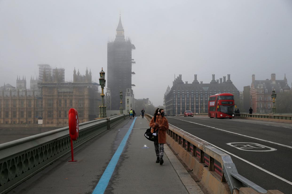 A woman wearing a face mask walks over Westminster Bridge, central London as England enters a second coronavirus lockdown on November 5, 2020. (Photo by Hollie Adams / AFP) (Photo by HOLLIE ADAMS/AFP via Getty Images)