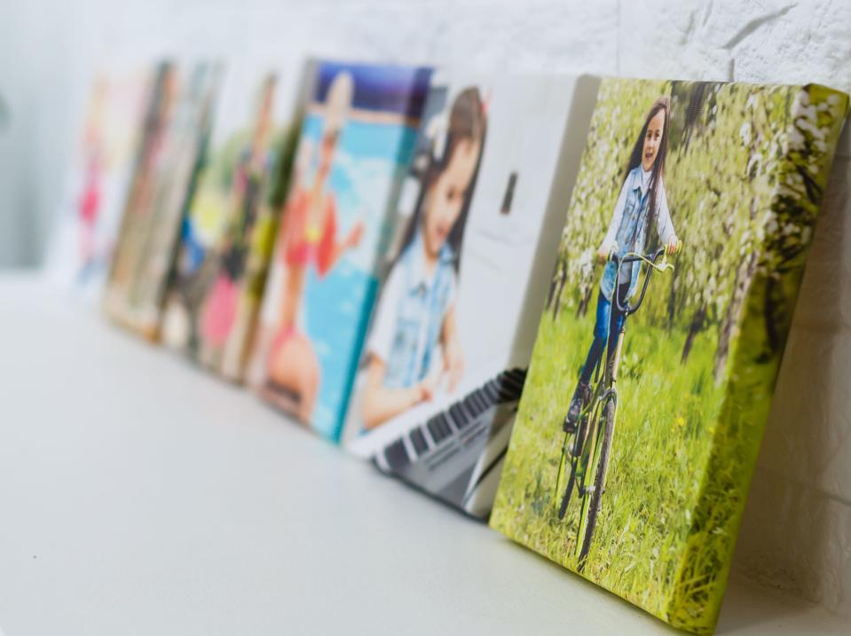 Family photos on canvas sitting in a row on a fireplace ledge