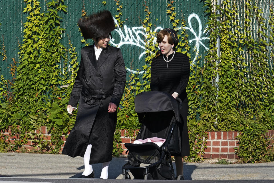 An Ultra-Orthodox man and woman cross a street, Sunday, Oct. 4, 2020, in the Borough Park neighborhood of New York on the Jewish holiday of Sukkot. Over the past two weeks, the number of new cases of coronavirus has been rising in pockets of the city, predominantly in neighborhoods in Queens and Brooklyn, including Borough Park, that are home to the city's large Orthodox Jewish population. (AP Photo/Kathy Willens)