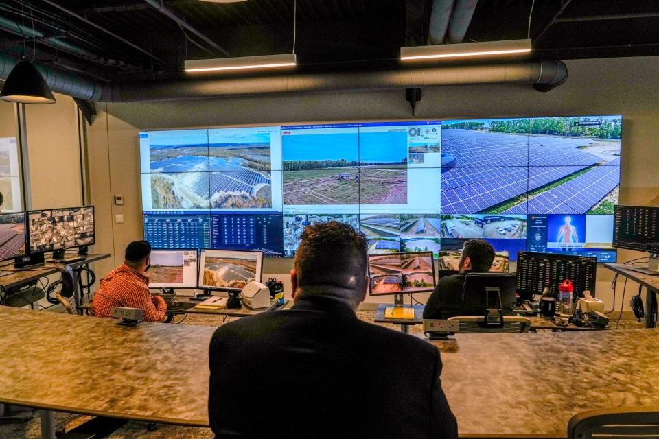 Mark DePasqule, owner of Green Development, with his technicians in the company's Cranston's office with images of several projects and live feeds on the monitors.