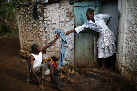 Cristera Jusma hands a towel to Enol St. Pierre as he gets ready to go to the church in Boucan Ferdinand, Haiti, April 8, 2018. REUTERS/Andres Martinez Casares