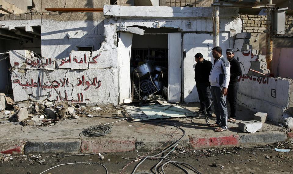 People gather at the site of a car bomb attack in the Risala district in Baghdad