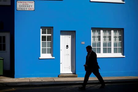 A man walks past a house in Chelsea in London August 13, 2013. Crises at home and turmoil on world markets may have taken the shine off London's luxuru property market for Chinese, Russian and Middle Eastern investors, some are even looking to sell up. REUTERS/Andrew Winning