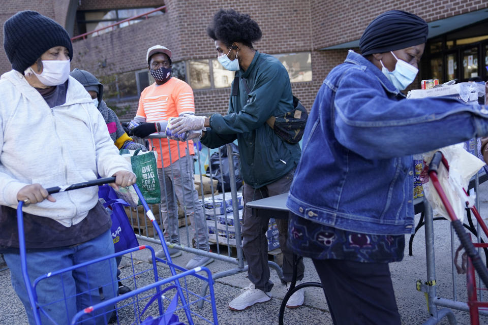 Volunteers and employees give out food to people waiting in line at the Doles Center in Mt. Vernon, N.Y., Monday, Nov. 16, 2020. While this particular aid was donated by Goya Foods, over the course of 2020 the city's recreation department is on track to give away almost three times more food, over one million pounds, than the usual amount they would help within a normal year. (AP Photo/Seth Wenig)