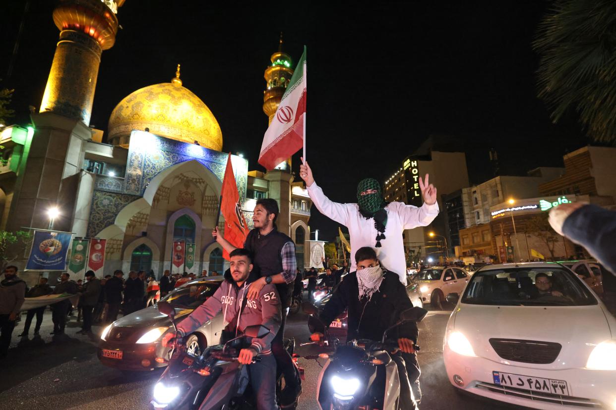 Demonstrators wave Iran's flag and Palestinian flags as they gather at Palestine Square in Tehran on April 14, 2024.