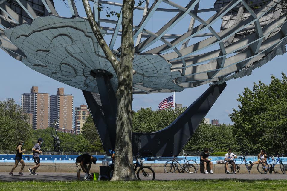 Runners and cyclists wear protective masks during the coronavirus pandemic as they pass the Unisphere, Tuesday, May 26, 2020, in the Queens borough of New York. (AP Photo/Frank Franklin II)