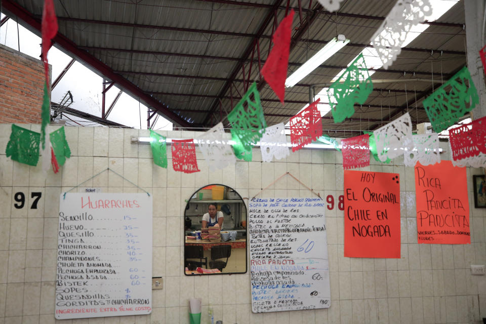 In this Sept. 10, 2019 photo, a sign advertises in Spanish, "Today, the traditional chile en nogada," at El Sabor, a family-owned restaurant inside the Juarez Market that for decades has been serving up chiles en nogada in the weeks leading up to Mexico's independence celebrations, in Mexico City. Although the 200 peso ($10.50) price tag at El Sabor is half that at high end restaurants, the traditional ingredients and hours of labor that go into making the sweet and salty dish mean it is still the priciest item on their menu, a seasonal treat for fans of the dish. (AP Photo/Rebecca Blackwell)