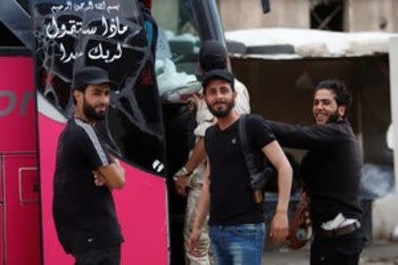 Rebel fighters carrying weapons, react before boarding a bus, as rebel fighters and their families evacuate the besieged Waer district, after an agreement was reached between rebels and Syria's army, in Homs, Syria May 20, 2017. REUTERS/Omar Sanadiki