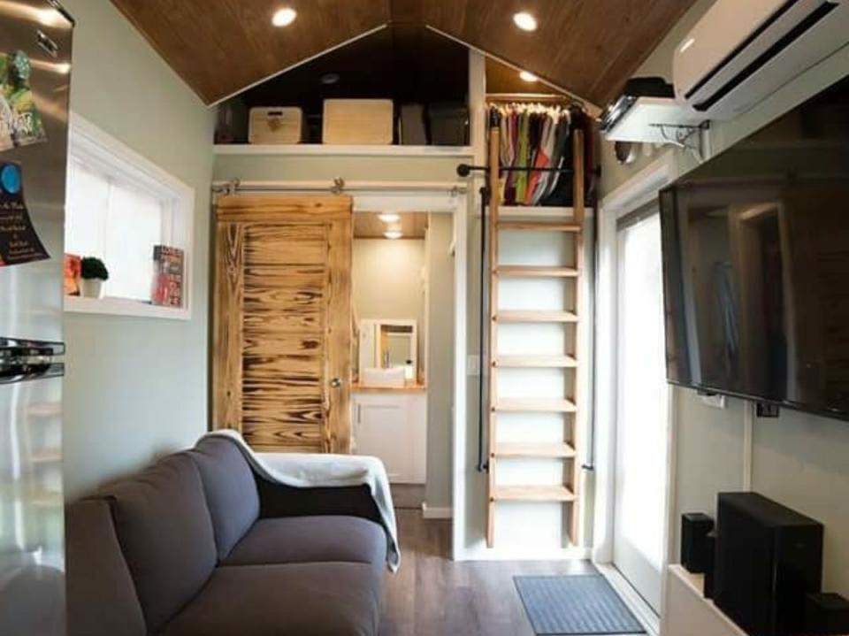 The living room with a couch and ladder to the loft in Marek and Ko Bush's tiny house