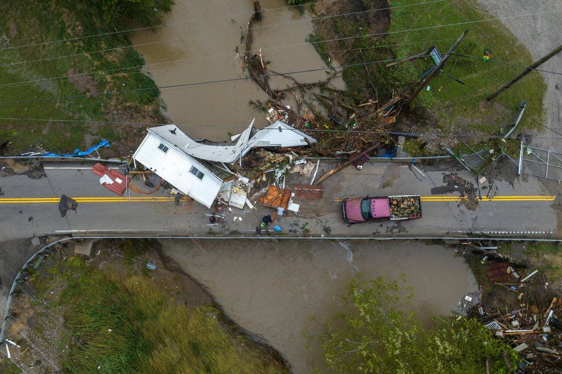 People work to clear a house from a bridge near the Whitesburg Recycling Center in Letcher County, Ky., on Friday, July 29, 2022.